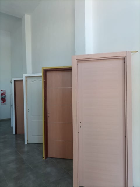 Collection of interior doors in different colors and styles displayed against white walls in an empty room