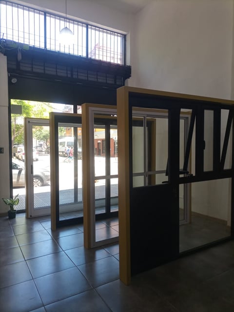 Modern storefront interior with glass entry doors, wooden frames, black partition walls, and tile flooring with street view through windows