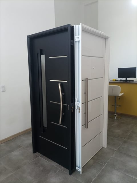Two modern interior doors displayed side by side in a showroom, one black with horizontal handles and one white with panel design